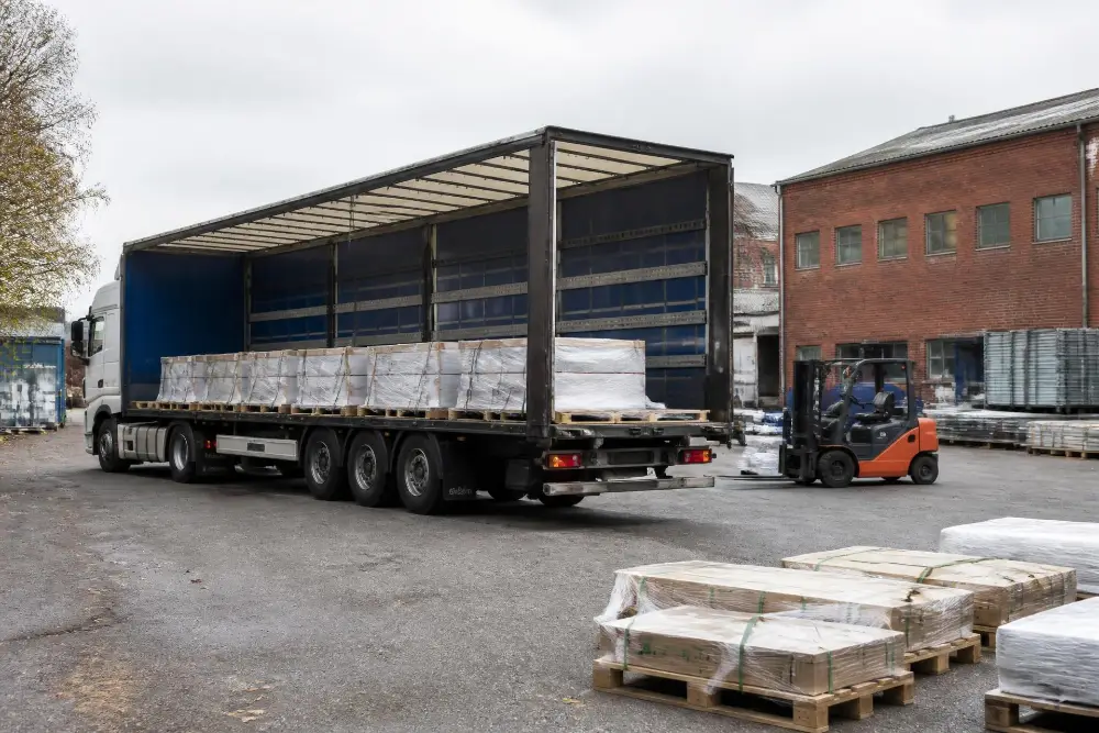 Lastbil och truck under pågående lossning på en industrigård